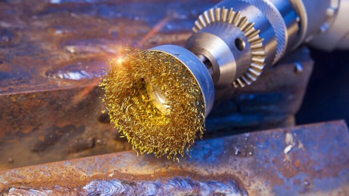 Drill with a wire cup brush removing loose rust from a steel surface