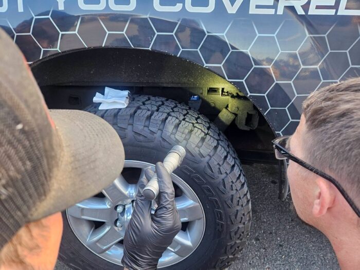 Technician inspecting the wheel well and suspension of a pickup truck